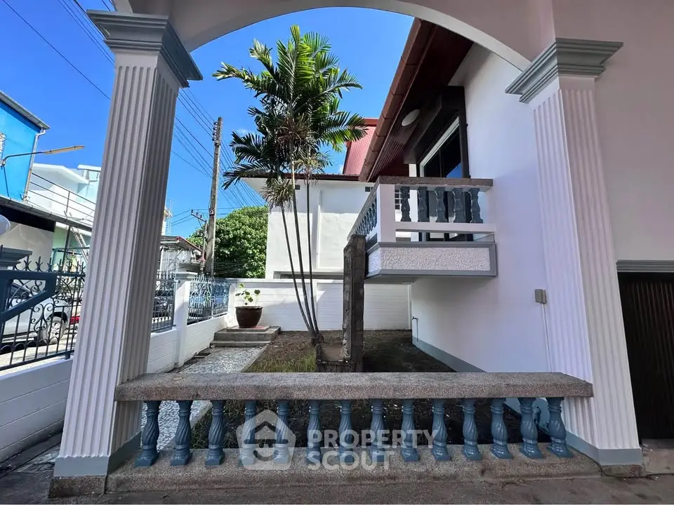 Charming exterior view of a modern home with elegant columns and lush greenery, perfect for tranquil living.
