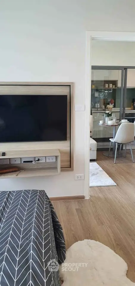 Modern living room with open layout and stylish decor, featuring a large TV and dining area.