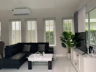 Modern living room with sleek black sofa, large windows, and stylish decor