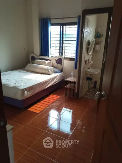 Cozy bedroom with attached bathroom and natural light through window.