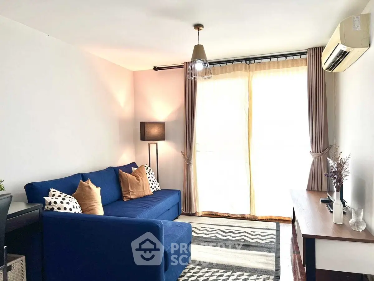 Bright living room with blue sofa, modern decor, and large window with curtains.