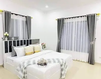 Elegant bedroom with modern decor and large windows, featuring stylish curtains and cozy bedding.