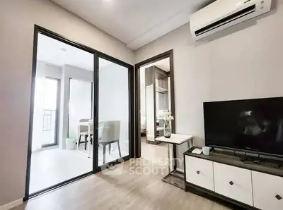 Modern living room with sleek design and air conditioning, featuring a TV and sliding glass doors.