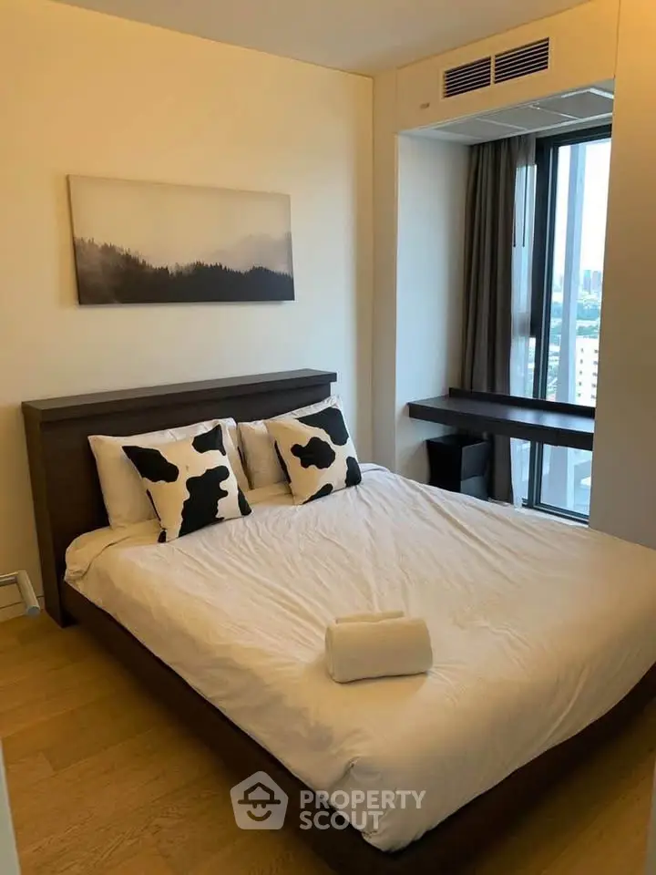 Modern bedroom with city view, featuring stylish decor and natural light.