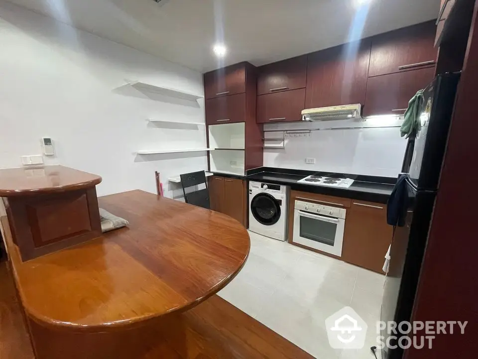 Modern kitchen with wooden cabinetry, washing machine, and built-in oven