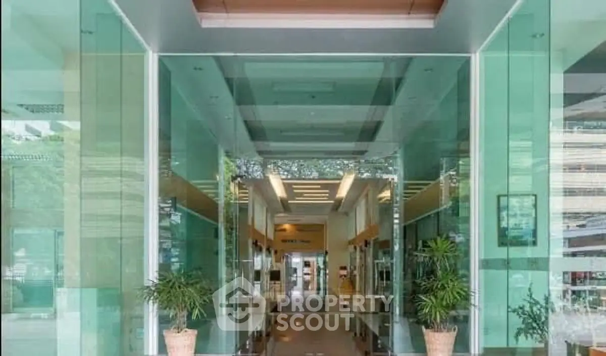 Modern building entrance with glass facade and potted plants