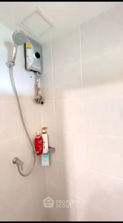 Modern bathroom shower area with sleek white tiles and showerhead