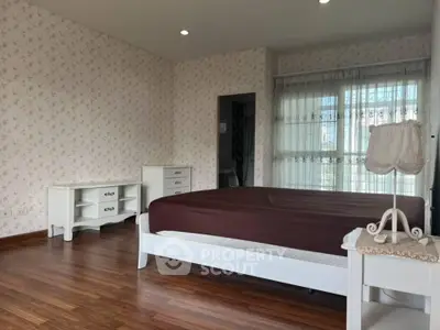 Spacious bedroom with elegant wooden flooring and classic white furniture