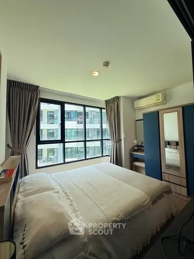 Modern bedroom with large windows and stylish decor in a high-rise apartment.