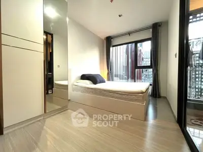Modern bedroom with large window and sleek furnishings in a stylish apartment.