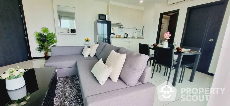 Modern open-plan living room with sleek kitchen and dining area, featuring stylish decor and ample natural light.