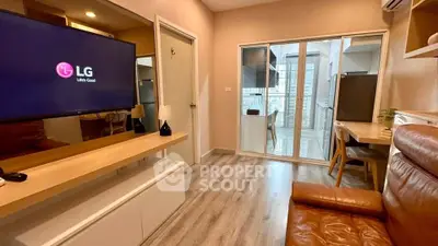 Modern living room with sleek furniture and large TV, adjacent to a glass-enclosed balcony.