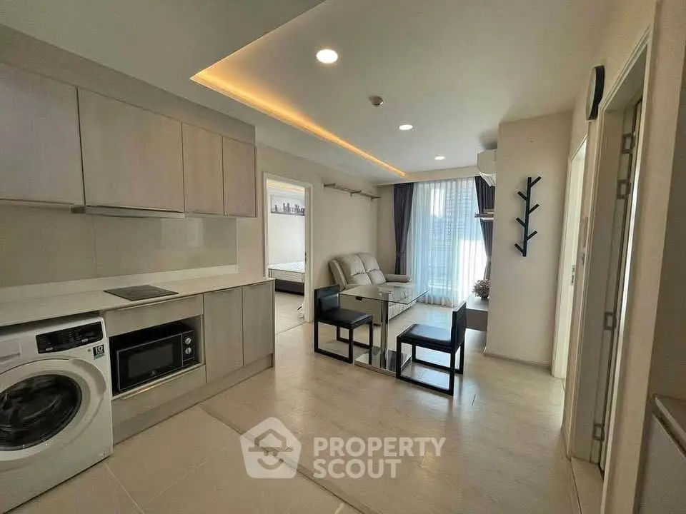 Modern open-plan living room with kitchen, featuring sleek furniture and natural light.