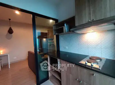 Modern kitchen with sleek black countertops and wooden cabinets in a cozy apartment setting.