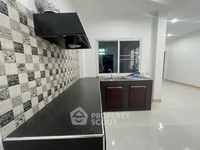 Modern kitchen with sleek black countertops and stylish backsplash in a spacious open layout.