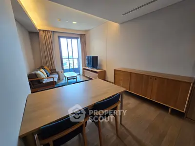 Modern living room with wooden furniture and large window offering natural light.