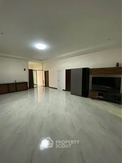 Spacious modern living room with sleek flooring and built-in entertainment unit.