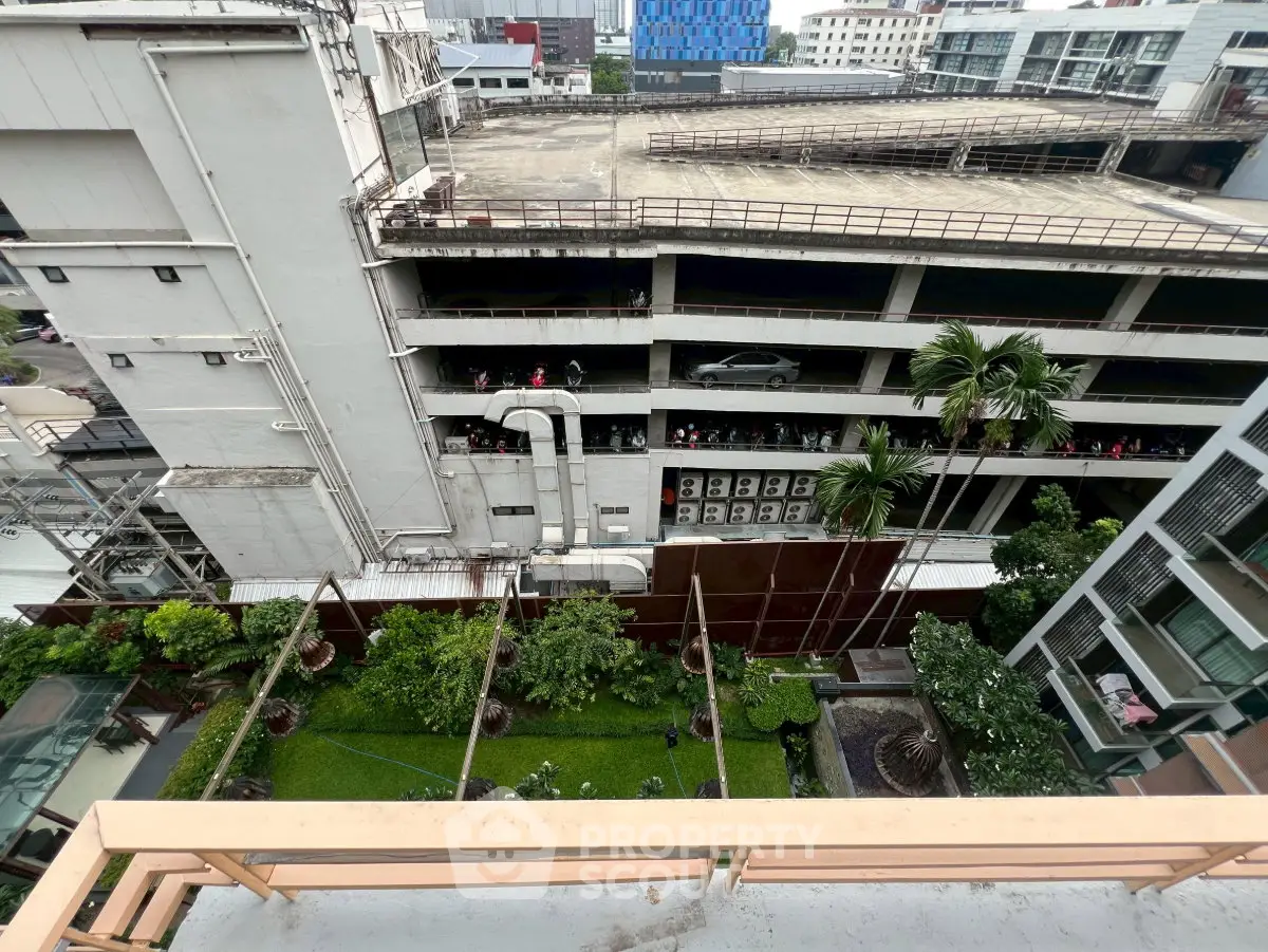 Urban view from balcony overlooking garden and parking structure