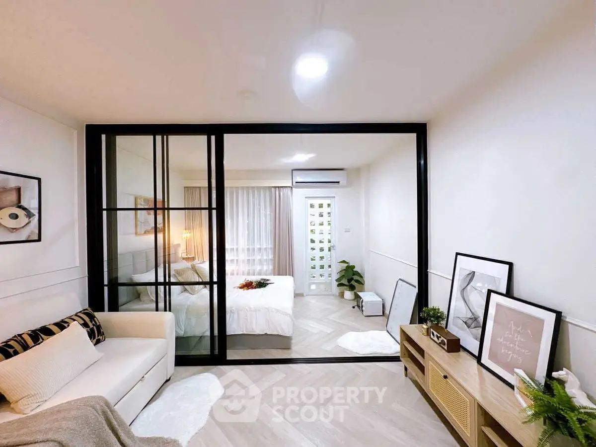 Modern apartment with stylish living room and cozy bedroom separated by glass partition.