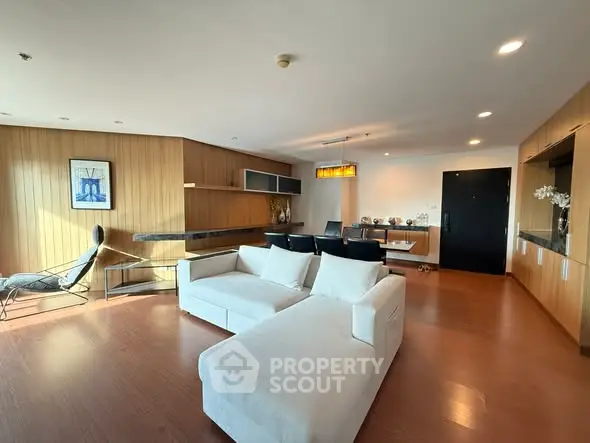 Spacious modern living room with elegant wooden accents and cozy white sofa, perfect for relaxation and entertaining.