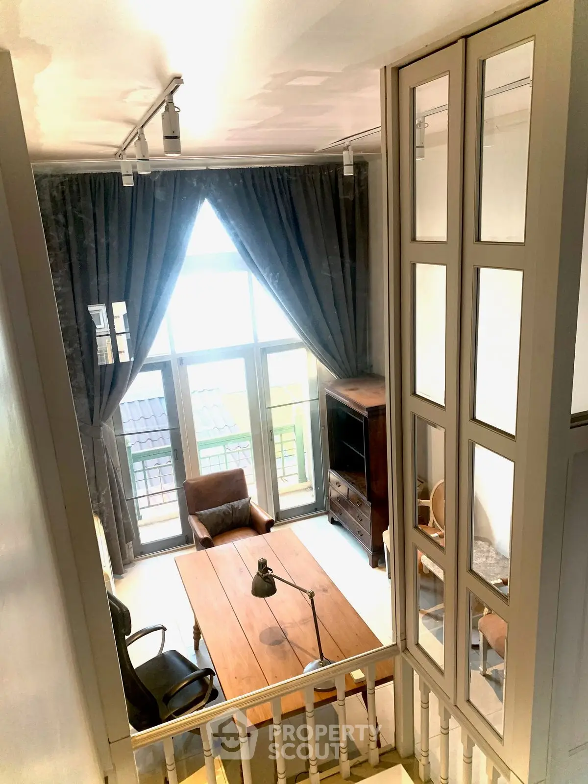 Charming loft-style living room with high ceilings and large windows, perfect for natural light lovers.