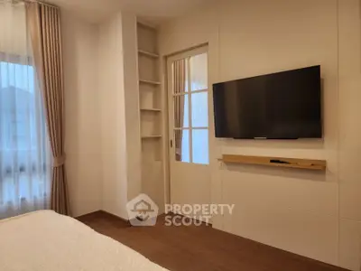 Modern bedroom with wall-mounted TV and elegant curtains