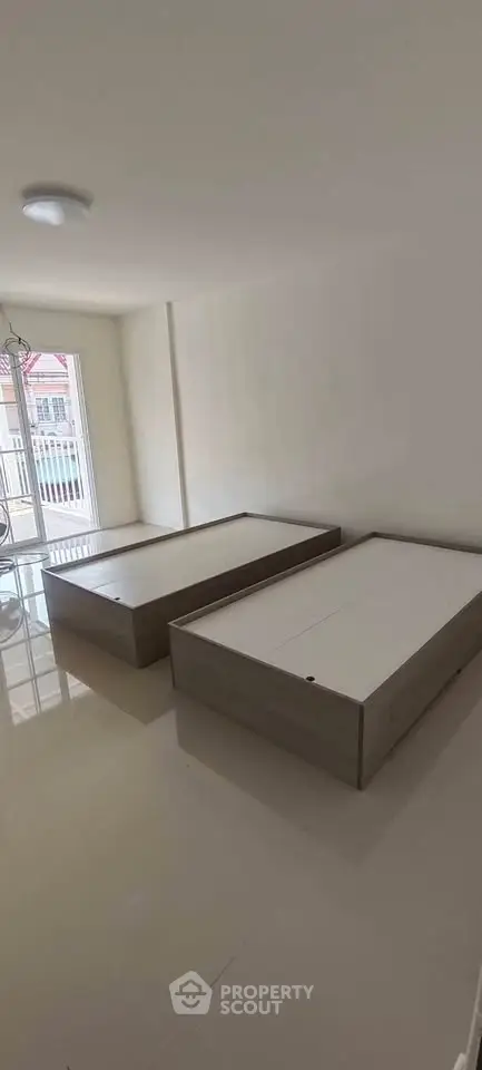 Spacious bedroom with twin beds and large window offering natural light.
