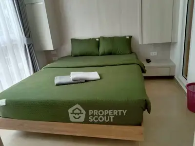 Modern bedroom with green bedding and natural light, perfect for relaxation and comfort.