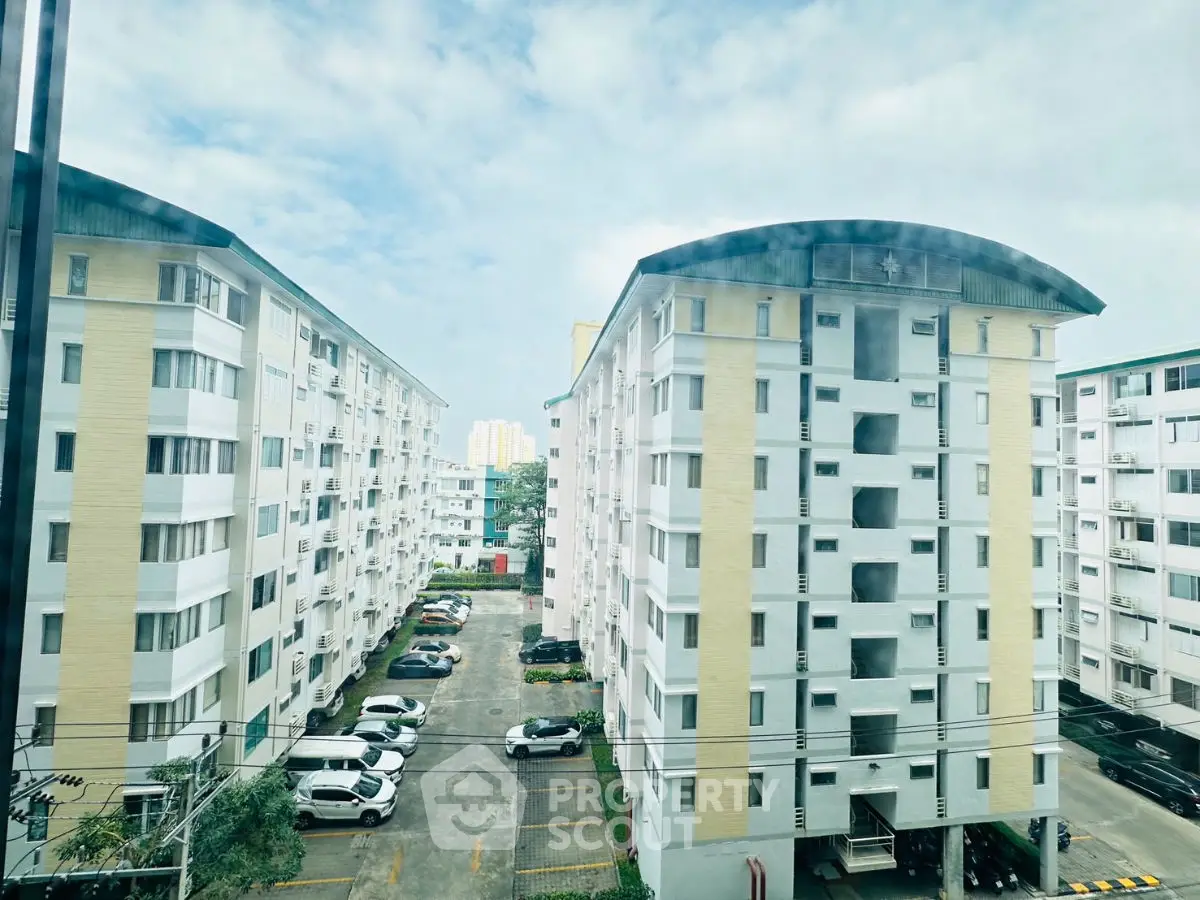 Modern apartment buildings with spacious parking area and clear blue sky.