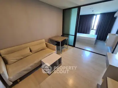 Modern studio apartment with cozy living area and bedroom separated by glass partition.
