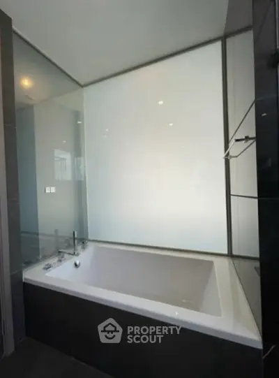 Modern bathroom with sleek bathtub and frosted glass panel