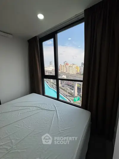Cozy bedroom with city view from large window, featuring a comfortable bed and modern design.