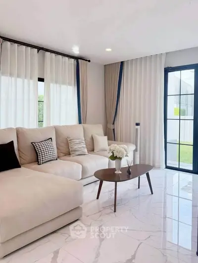 Elegant living room with modern decor, large windows, and stylish furniture, perfect for relaxation and entertaining.