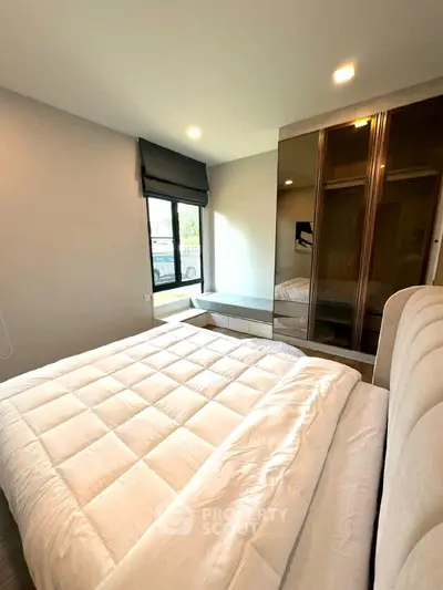 Modern bedroom with large window and mirrored wardrobe, featuring a cozy bed and stylish decor.