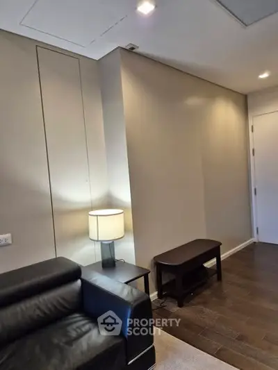 Modern living room with sleek black leather sofa and stylish lamp