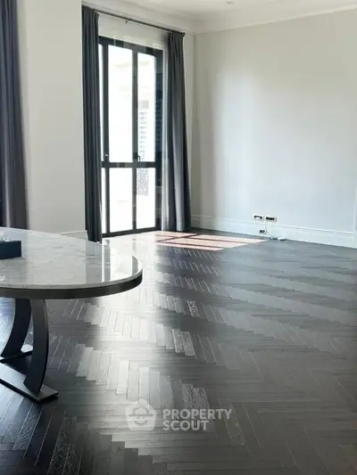 Spacious living room with elegant dark wood flooring and large window for natural light.