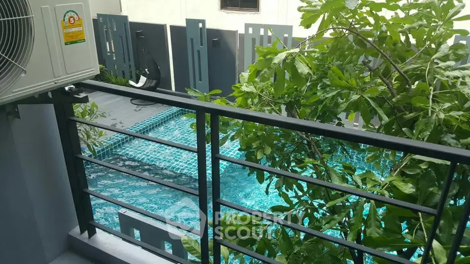 Modern balcony view overlooking a stylish swimming pool with lush greenery.