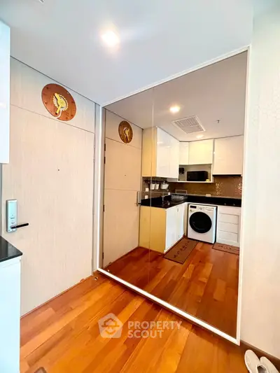 Modern kitchen with sleek appliances and wooden flooring in a stylish apartment.