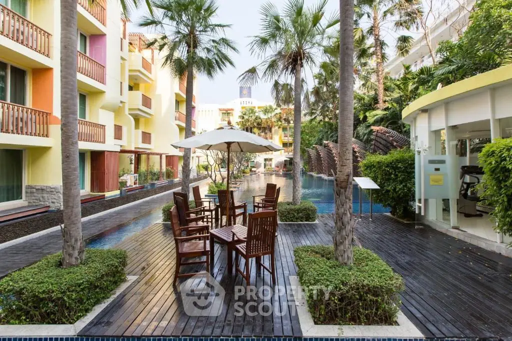 Luxurious poolside view with elegant outdoor seating and lush greenery in a modern apartment complex.
