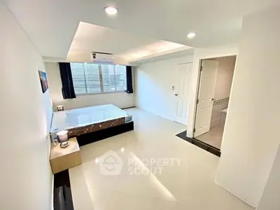 Spacious modern bedroom with minimalist design and ample natural light.