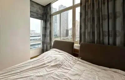 Modern bedroom with large windows offering stunning city views in a high-rise apartment.
