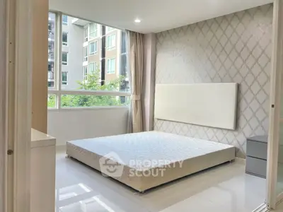 Bright modern bedroom with large window and elegant wallpaper in urban apartment.
