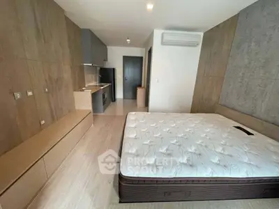 Modern studio apartment with sleek kitchen and cozy bedroom area, featuring wood accents and air conditioning.