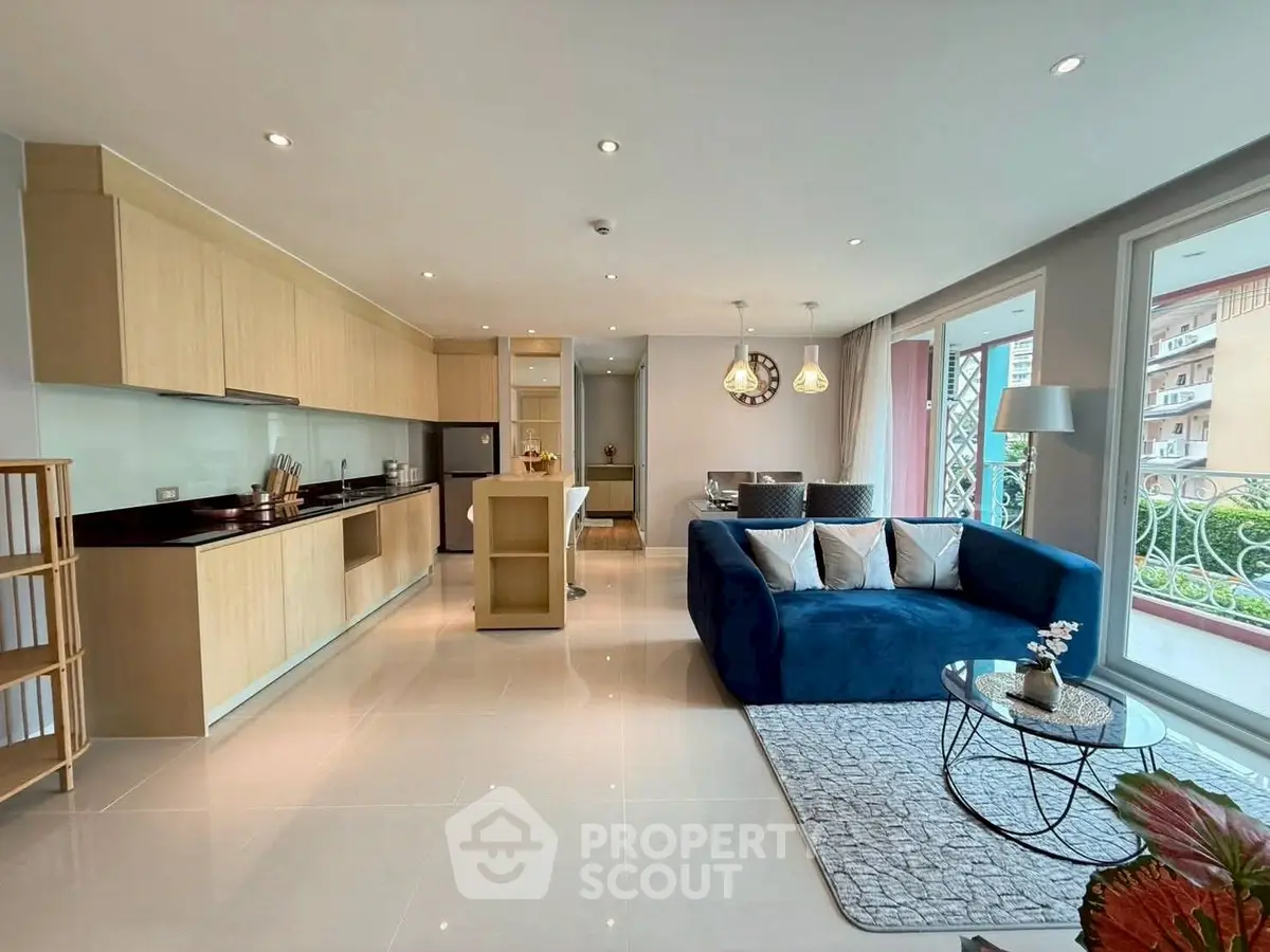 Modern open-plan living room with sleek kitchen and stylish blue sofa
