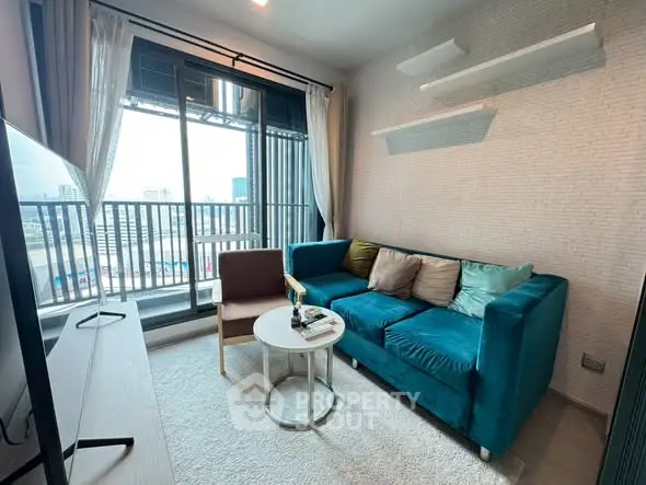 Modern living room with teal sofa and city view balcony in high-rise apartment.