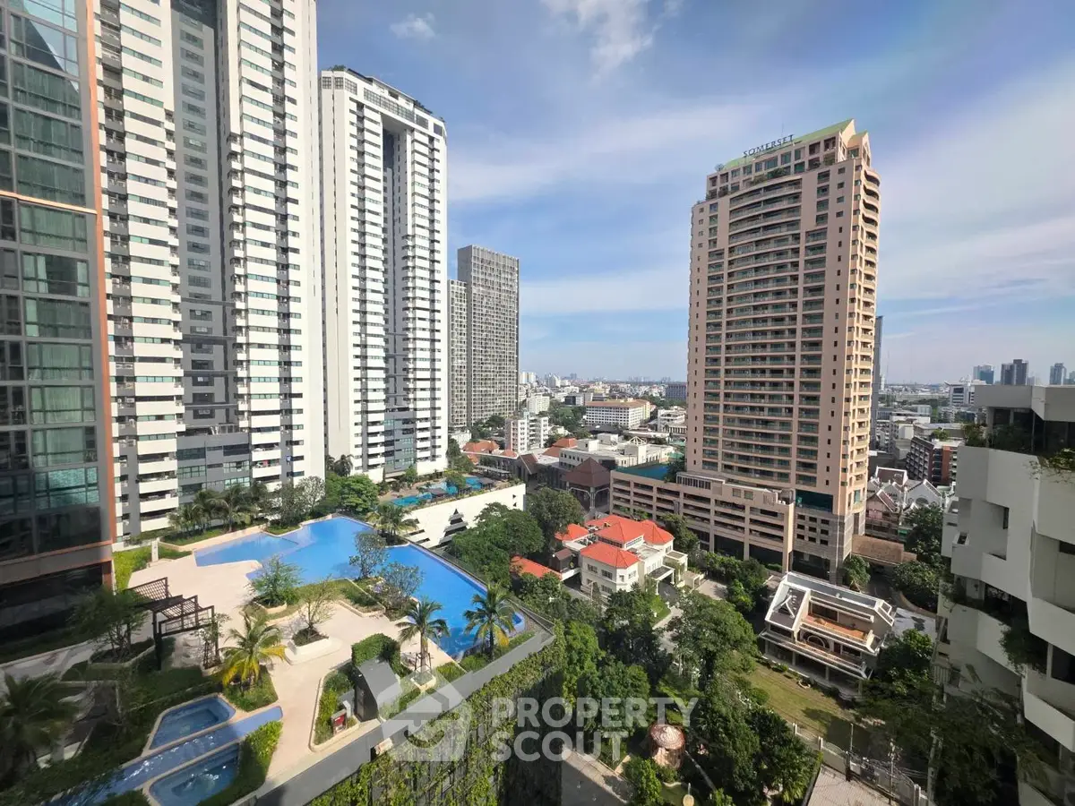 Stunning cityscape view from high-rise apartment with pool and lush greenery.