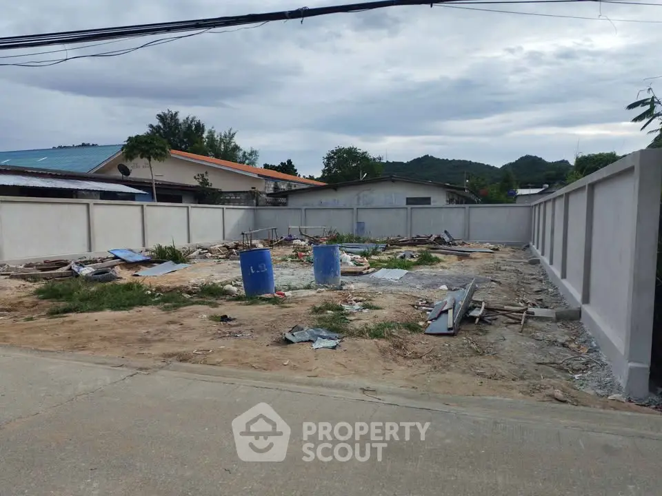 Vacant land plot with potential for development, surrounded by a concrete wall, ideal for new construction.