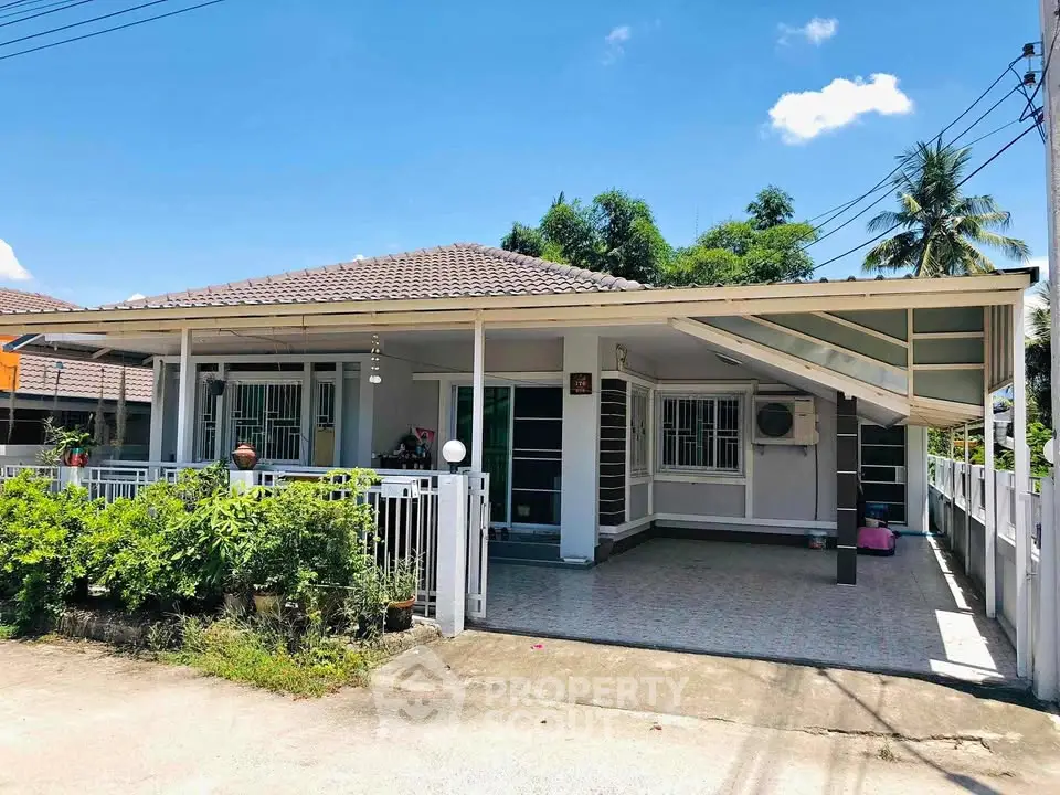 Charming single-story house with carport and lush greenery in a serene neighborhood.