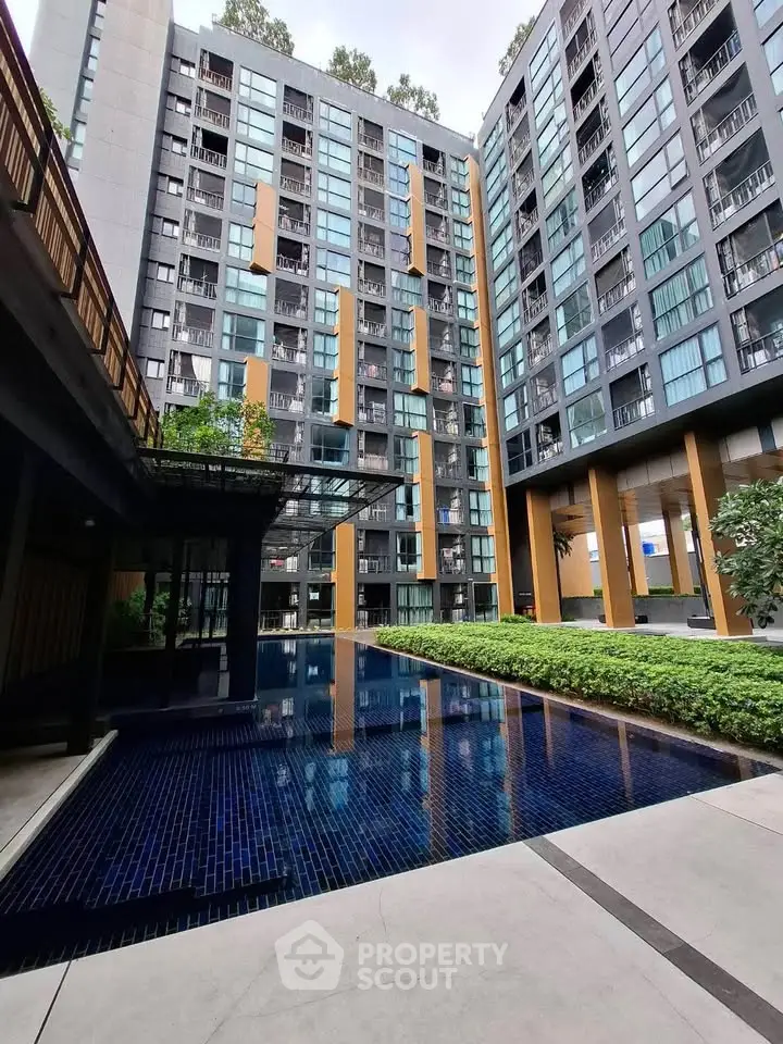 Modern condominium with pool and lush greenery in urban setting