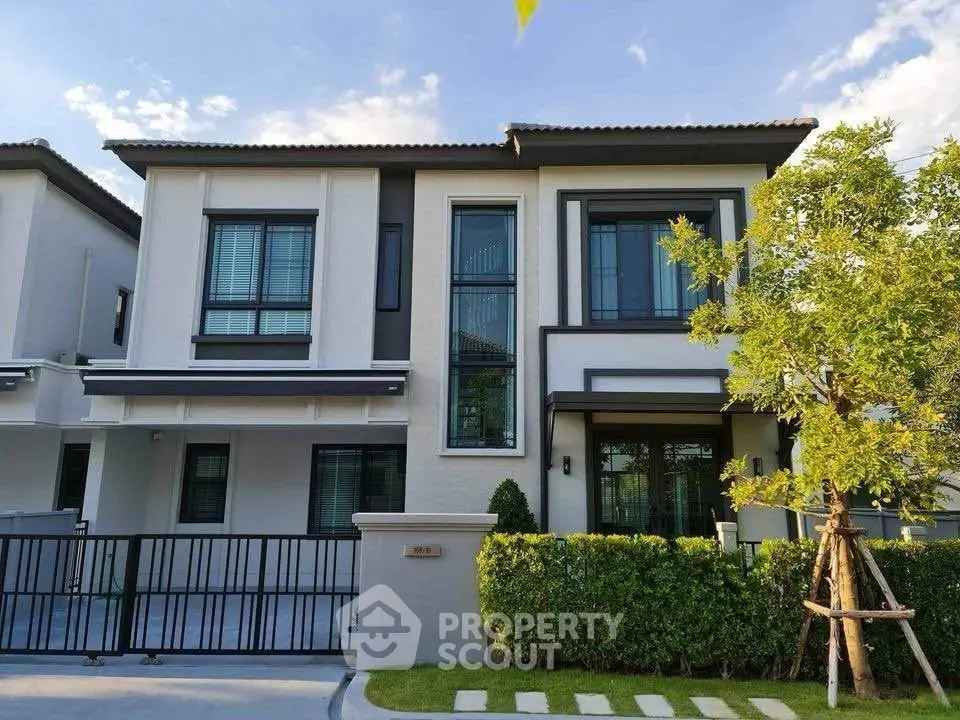 Modern two-story house with large windows and landscaped front yard in a serene neighborhood.